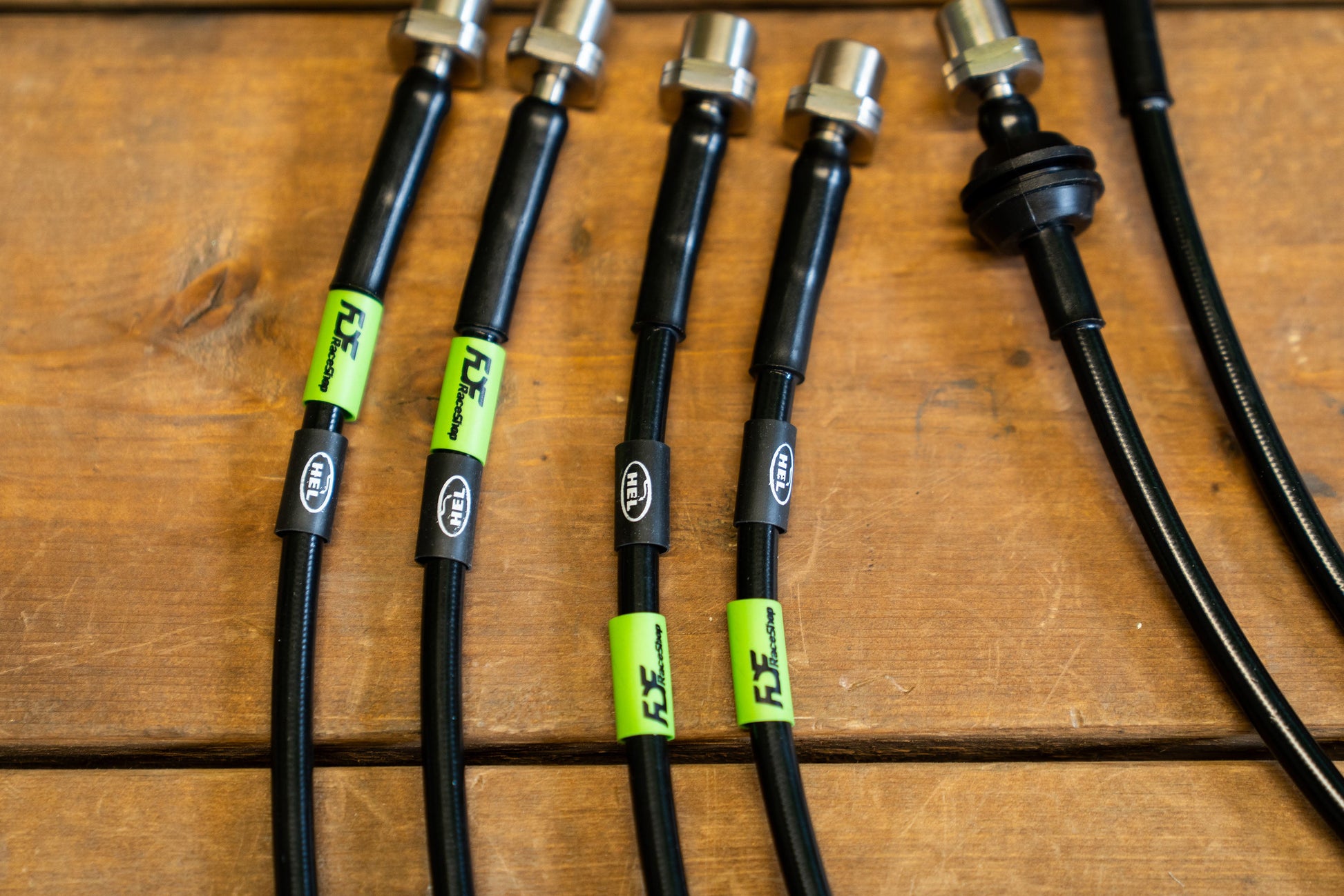 Black cables with green labels on a wooden surface